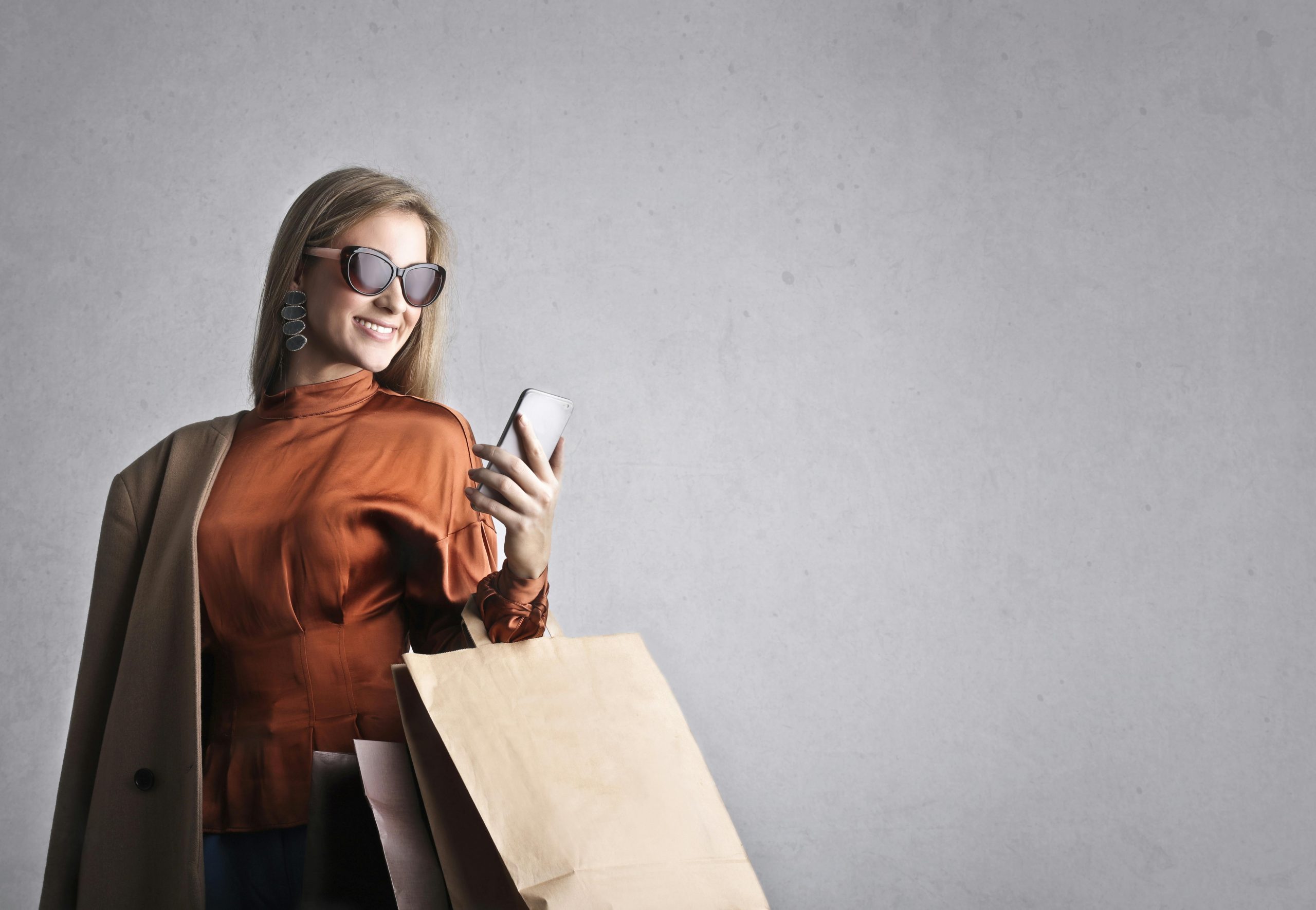 stylish woman holding shopping bags and a smartphone